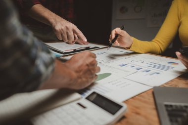 Gelirleri hesaplamak için birlikte çalışan bir grup işadamı, finansal rakamları gözden geçiriyorlar, finansal belgeleri çıkarıyorlar ve onları bir hesap makinesiyle, finansal fikirle kontrol ediyorlar..