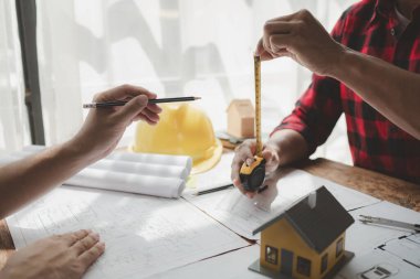 Yapısal işlerde kullanım için tasarım planları, toplantıda binaların yapısını çizin ve birlikte tartışın, mühendis mimarla bir ev inşa etme konusunda planlama yapıyor, mimar fikri.