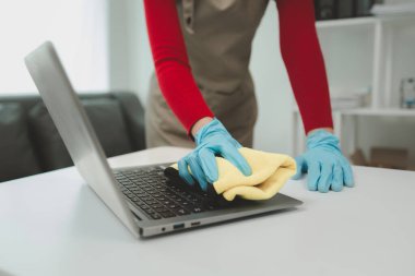 Ofisi temizleyen, defteri paçavrayla temizleyen, eldiven takan, havluyla silen, temizlik yaparken lastik eldiven takan, temizlikçi..