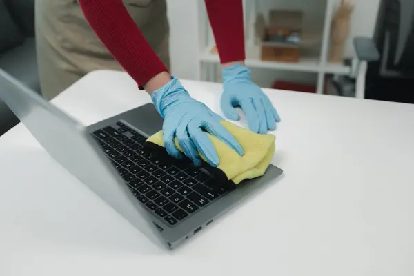 Janitor cleaning the office,  Clean the notebook with a rag, wear gloves and wipe with a towel, Wear rubber gloves when working with cleaning chemicals, cleaning idea.