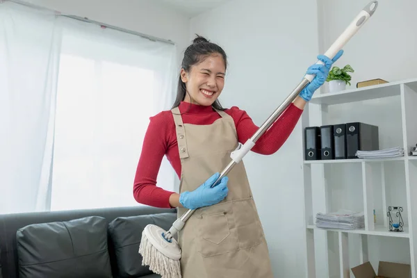 Asian women wear uniforms to prepare for housekeeping work, Wear an apron and rubber gloves to protect against cleaning chemicals, housekeeper is smiling happily before starting work, cleaning idea.