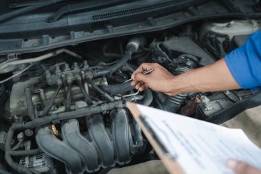 Tamirci motoru tamir ediyor, bir araba tamircisi arabayı inceliyor, bir araba tamircisi garajdaki motorla ilgili sorunu araştırıyor..