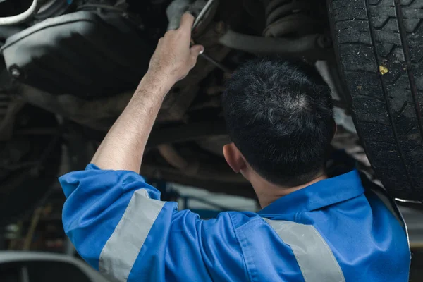The mechanic is repairing the engine, A car repair worker is inspecting a car, A car mechanic is looking at what is the problem with the engine in the garage.