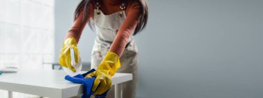 Ofisteki masa yüzeyini dezenfektan spreyiyle temizlemek, eldiven giymek ve masayı havluyla silmek, temizlikçi, temizlik için çalışma masasını temizliyor çünkü Covid-19, temizlik fikri....