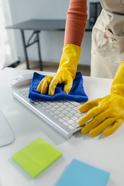 Ofis ekipmanlarını temizleme, klavyeyi havlu ve dezenfektanla silme, temizlik kimyasallarıyla çalışırken lastik eldiven giyme, temizlik fikri..