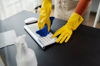 Ofis ekipmanlarını temizleme, klavyeyi havlu ve dezenfektanla silme, temizlik kimyasallarıyla çalışırken lastik eldiven giyme, temizlik fikri..