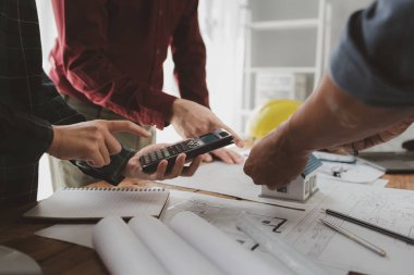 Mimarlar ve mühendisler ev yapımı sorunlarına çözüm bulmak için birlikte çalışırlar, mülk bir grup mühendis tarafından tasarlanmak üzeredir, mimarlar birlikte planlarını gözden geçiriyorlar..