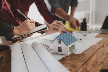 Mimarlar ve mühendisler ev yapımı sorunlarına çözüm bulmak için birlikte çalışırlar, mülk bir grup mühendis tarafından tasarlanmak üzeredir, mimarlar birlikte planlarını gözden geçiriyorlar..
