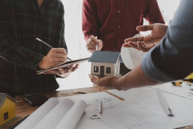 Mimarlar ve mühendisler ev yapımı sorunlarına çözüm bulmak için birlikte çalışırlar, mülk bir grup mühendis tarafından tasarlanmak üzeredir, mimarlar birlikte planlarını gözden geçiriyorlar..