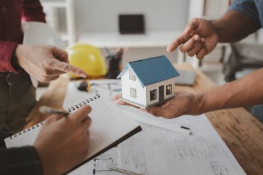 Mimarlar ve mühendisler ev yapımı sorunlarına çözüm bulmak için birlikte çalışırlar, mülk bir grup mühendis tarafından tasarlanmak üzeredir, mimarlar birlikte planlarını gözden geçiriyorlar..