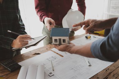 Mimarlar ve mühendisler ev yapımı sorunlarına çözüm bulmak için birlikte çalışırlar, mülk bir grup mühendis tarafından tasarlanmak üzeredir, mimarlar birlikte planlarını gözden geçiriyorlar..