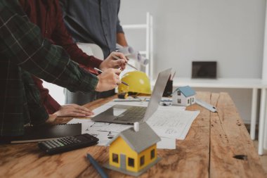 Mimarlar ve mühendisler ev yapımı sorunlarına çözüm bulmak için birlikte çalışırlar, mülk bir grup mühendis tarafından tasarlanmak üzeredir, mimarlar birlikte planlarını gözden geçiriyorlar..