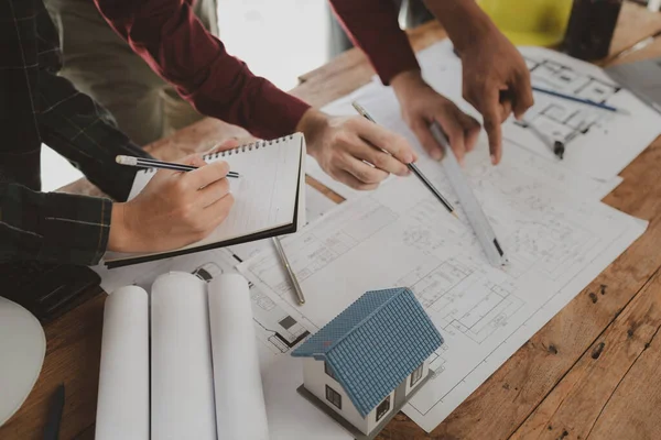Mimarlar ve mühendisler ev yapımı sorunlarına çözüm bulmak için birlikte çalışırlar, mülk bir grup mühendis tarafından tasarlanmak üzeredir, mimarlar birlikte planlarını gözden geçiriyorlar..