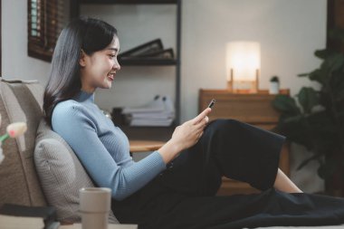 Kadın kanepede oturuyor, rahat bir şekilde kanepede oturuyor, tatilde evdeki oturma odasında dinleniyor, rahat bir hayat yaşıyor, dairedeki kanepede oturuyor..