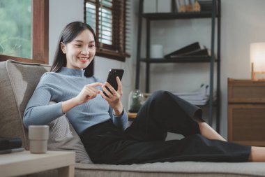 Kadın kanepede oturuyor, rahat bir şekilde kanepede oturuyor, tatilde evdeki oturma odasında dinleniyor, rahat bir hayat yaşıyor, dairedeki kanepede oturuyor..