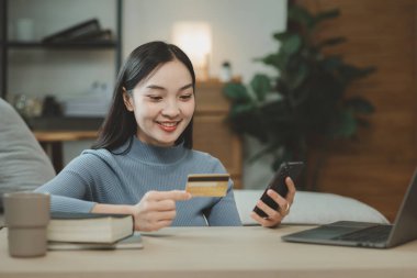 Oturma odasındaki kanepede online alışveriş yapmak, izin günlerinde internet üzerinden ödeme yapmak için kredi kartı kullanmak, hizmet parasını ödemek için kredi kartı bilgilerini girmek için dizüstü bilgisayar kullanmak..