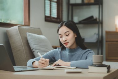 Bir öğrenci oturma odasında oturup ödev yapıyor, bilgi topluyor ve evdeki öğretmenlere göndermek için raporlar hazırlıyor, apartmandaki kitaptaki çeşitli bilgileri kaydediyor..