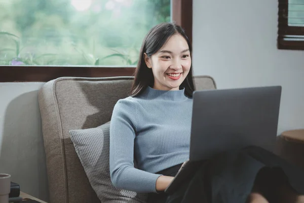 Woman is sitting and relaxing on the couch, Relax in the living room at home on holiday, Woman using laptop to relax in living room, relaxing idea, Sit back and relax happily in the house.