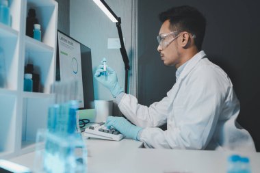 Kimyager test tüplerini kimyasal olarak analiz ediyor. Bilim adamı laboratuvarda kimyasallar üzerinde deney yapıyor. Kimyager test tüplerindeki bileşikleri kimyasal reaktörlerle ayırıyor..