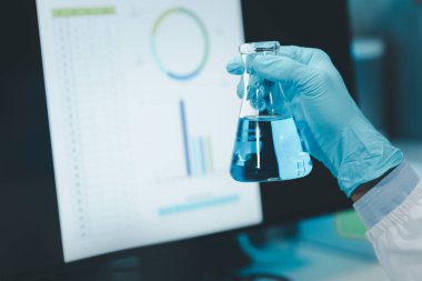 Kimyager test tüplerini kimyasal olarak analiz ediyor, kimyager laboratuvarda bir deney yapıyor, kimyacı araştırma verileri üzerine notlar alıyor, bilim adamı laboratuarda çalışıyor., 