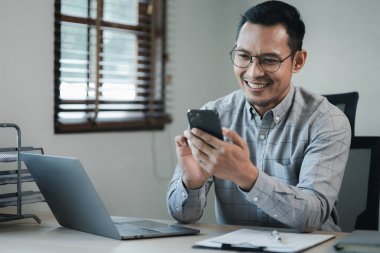 İşadamı ofiste çalışıyor ve bir ortakla telefonda konuşuyor, girişimciler bunu sunmak için akıllı telefonları kullanıyor, bir şirkette özel bir ofiste çalışıyor..