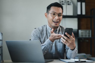 İşadamı ofiste çalışıyor ve bir ortakla telefonda konuşuyor, girişimciler bunu sunmak için akıllı telefonları kullanıyor, bir şirkette özel bir ofiste çalışıyor..