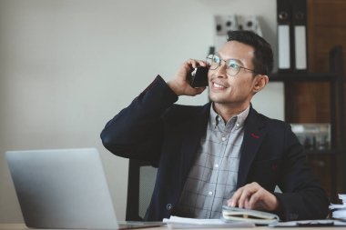 İşadamı ofiste çalışıyor ve bir ortakla telefonda konuşuyor, girişimciler bunu sunmak için akıllı telefonları kullanıyor, bir şirkette özel bir ofiste çalışıyor..