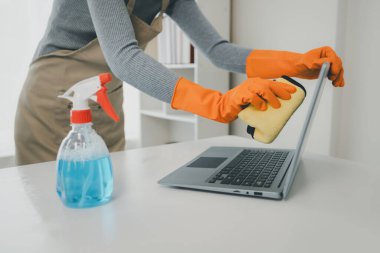 Ofis ekipmanlarını temizleyen, defteri paçavrayla temizleyen, ofisi temizleyen, lastik eldiven ve önlük giyen ve mutlu bir gülümsemeyle çalışan., 