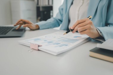İş kadını ofiste oturuyor ve çalışıyor, Çalışan bilgisayarda bilgi arıyor, çeşitli bilgileri kağıda kaydediyor., 