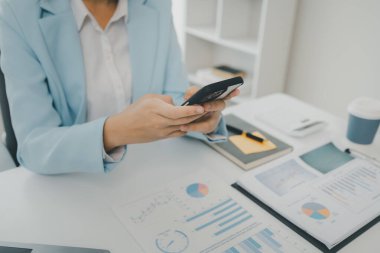 Bir girişimci, bir şirket müşterisiyle telefonda konuşuyor. İş kadını ofiste oturuyor ve çeşitli bilgileri kağıda kaydediyor.,