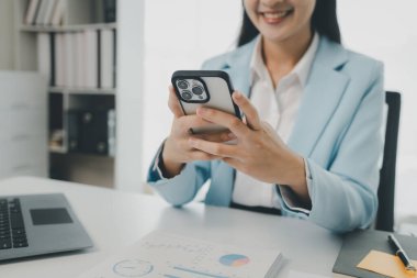 Bir girişimci, bir şirket müşterisiyle telefonda konuşuyor. İş kadını ofiste oturuyor ve çeşitli bilgileri kağıda kaydediyor.,