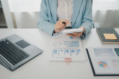 Muhasebe analisti, şirketin mali tablolarındaki bakiyeleri hesaplamak için hesap makinesine basıyor, rakamları hesaplıyor, mali tabloları ve muhasebeyi hazırlıyor, finansal muhasebe kavramlarını hesaplıyor.