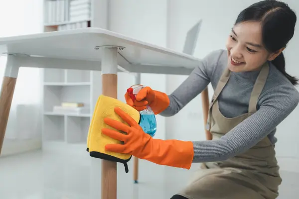 Cleaning staff wiping down office equipment, Asian women wear uniforms to prepare for housekeeping work, Wear rubber gloves when working with cleaning chemicals,