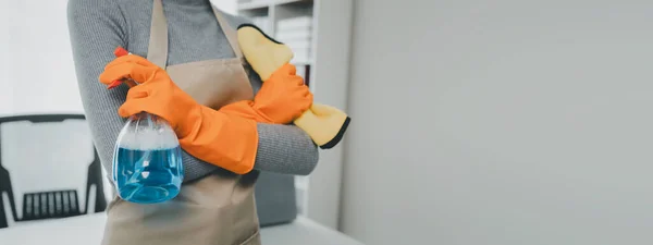 Wear an apron and rubber gloves to protect against cleaning chemicals, Janitor cleaning the office, Use a towel to wipe the table, Wear rubber gloves when working with cleaning chemicals,