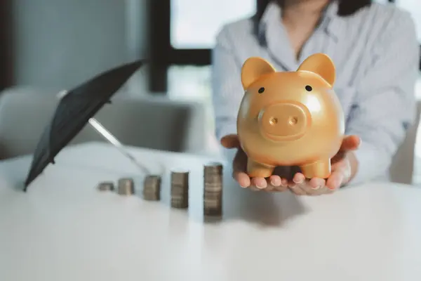 The financial worker held out a piggy bank, An accountant holds an umbrella over a piggy bank, Employees demonstrate how to care for customer assets that will be invested.