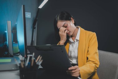 Asyalı kadın dizüstü bilgisayarla çalışırken stresli, ofiste başı ağrıyan Asyalı iş kadını, işte kendini hasta hissediyor, stresli, endişeli görünen olgun iş kadını.