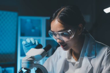 Coronavirus aşısı geliştirmek için mikroskopla çalışan biyokimyasal araştırmacı Gözlüklü Güzel Kadın Bilimadamının Portresi Test Analizi için Mikropipet Kullanıyor.