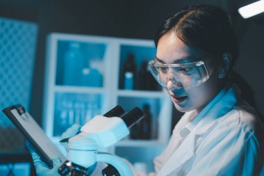 Coronavirus aşısı geliştirmek için mikroskopla çalışan biyokimyasal araştırmacı Gözlüklü Güzel Kadın Bilimadamının Portresi Test Analizi için Mikropipet Kullanıyor.