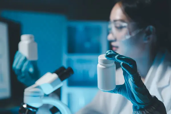 biochemical research scientist working with microscope for coronavirus vaccine development in, Portrait of a Beautiful Female Scientist in Goggles Using Micropipette for Test Analysis.