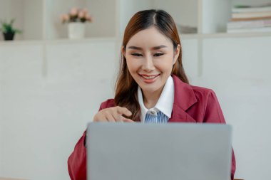 İş kadını ofiste oturuyor ve çalışıyor, Çalışan laptopta bilgi arıyor, çeşitli bilgileri kağıda kaydediyor, çalışanlar oturuyor ve ofiste notlar alıyor.