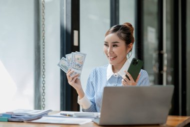 Bir işletme sahibi, bir finans kitabına para sayıyor ve notlar alıyor, finansör, müşterinin yatırımından elde edilen geliri teyit ediyor., 