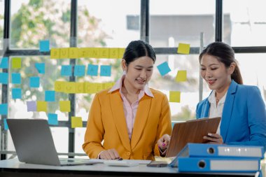 İş arkadaşlarıyla tartışan kendine güvenen kadın yöneticiler, dizüstü bilgisayarla çalışan yöneticiler masada oturup şirket toplantısında dijital stratejiyi tartışıyorlar..