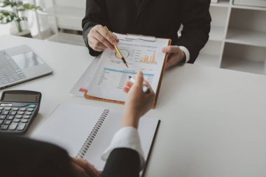 Gelir hesaplamak için birlikte çalışan bir grup işadamı, finansal rakamları gözden geçiriyorlar, finansal belgeleri çıkarıyorlar ve hesap makinesiyle kontrol ediyorlar.,