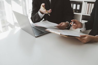 Gelir hesaplamak için birlikte çalışan bir grup işadamı, finansal rakamları gözden geçiriyorlar, finansal belgeleri çıkarıyorlar ve hesap makinesiyle kontrol ediyorlar.,