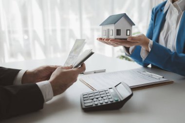 Komisyoncu alıcıdan ev alımının ilk taksitini alır, müşterilerden ev taksitlerini sayar, ev satış bürosundaki müşteriyle görüşmek için randevu alır..