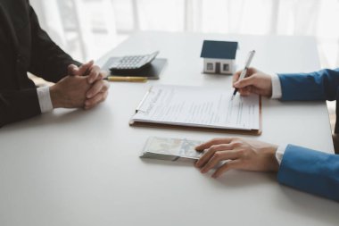 Komisyoncu alıcıdan ev alımının ilk taksitini alır, müşterilerden ev taksitlerini sayar, ev satış bürosundaki müşteriyle görüşmek için randevu alır..