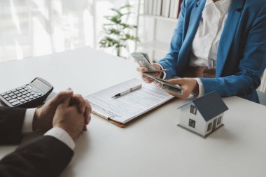 Komisyoncu alıcıdan ev alımının ilk taksitini alır, müşterilerden ev taksitlerini sayar, ev satış bürosundaki müşteriyle görüşmek için randevu alır..