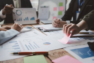 Finansal belgeleri al ve hesap makinesiyle kontrol et, şirket içindeki harcamalar için finansman planlıyorlar, toplantıya gönderilen rapora göre rakamları hesaplıyorlar., 