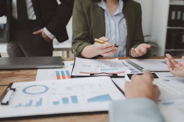 Finansal belgeleri al ve hesap makinesiyle kontrol et, şirket içindeki harcamalar için finansman planlıyorlar, toplantıya gönderilen rapora göre rakamları hesaplıyorlar., 