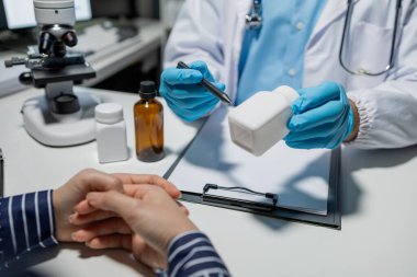 Doktor ve hasta, ilaç tarifi hakkında konuşuyor. Profesyonel doktor, beyaz önlük giyiyor. Yetişkin bir kadınla konuşuyor.,